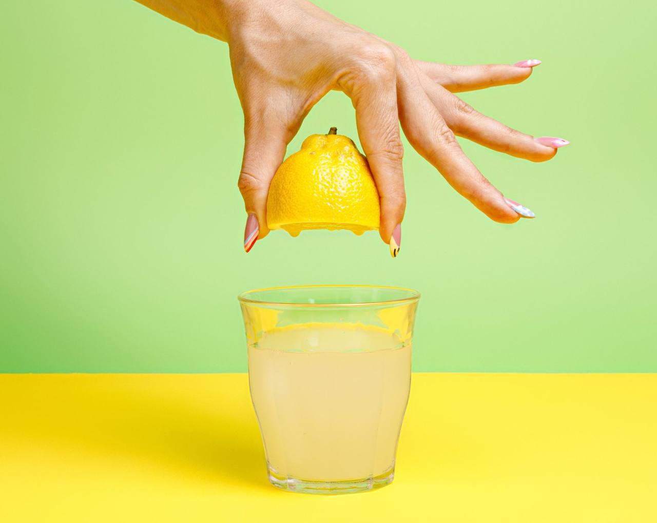 Bir bardak limonatanın üzerine yarım limonu elle sıkmak